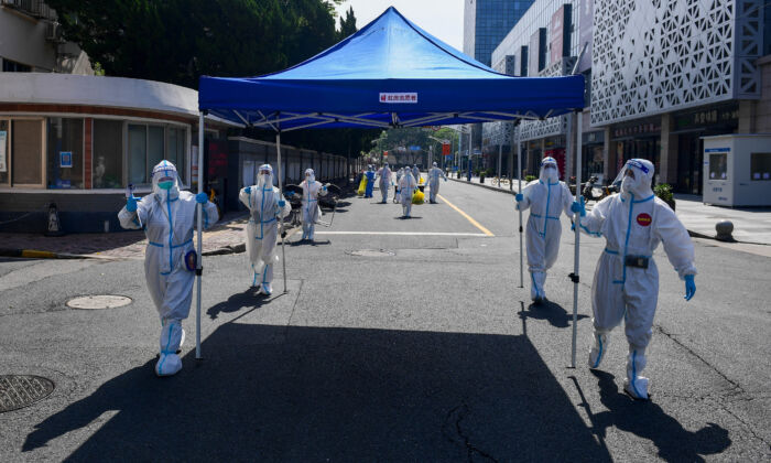 Workers in protective suits move equipment for a makeshift nucleic acid testing site to the next residential area after wrapping up the screening at a compound in Shanghai on May 14, 2022. (cnsphoto via Reuters)