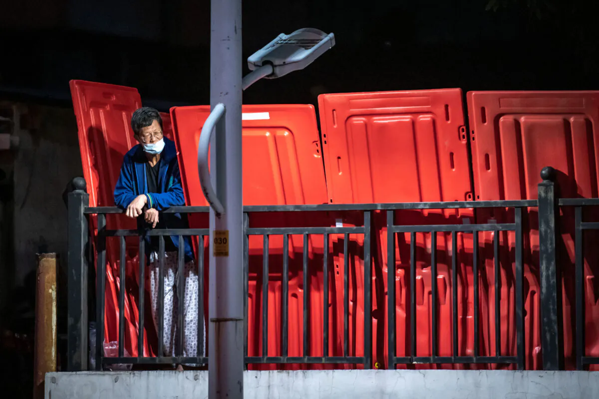 A resident stands next to barriers as an area is blocked off amid COVID outbreak in Guangzhou in China's southern Guangdong Province. (STR/AFP via Getty Images)