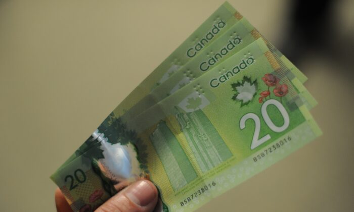 A man displays Canadian $20 bills in a file photo. (Nicholas Kamm/AFP via Getty Images)