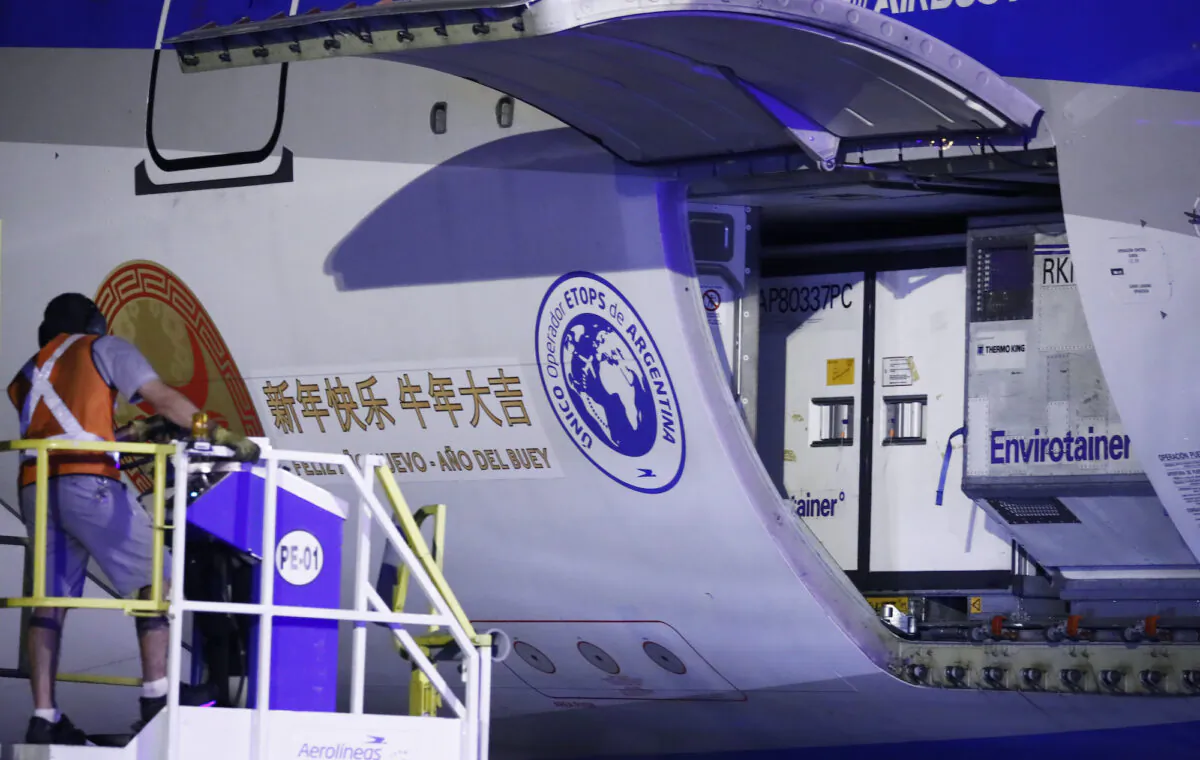 A worker unloads containers on an Airbus 330-200 of Aerolineas Argentinas carrying 904,000 doses of Sinopharm vaccines after it arrived at Ezeiza International Airport from China in Ezeiza, Argentina, on Feb. 25, 2021. (Marcos Brindicci/Getty Images)