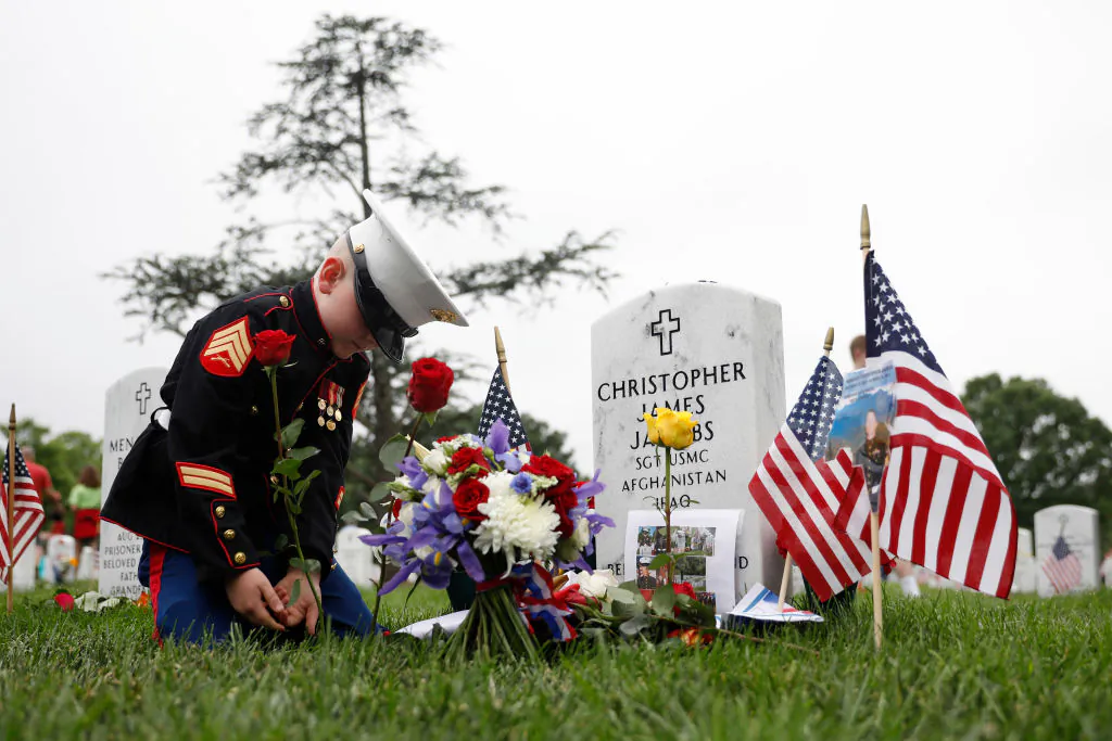 Christian Jacobs places a flower near the headstone of his father, Marine Sgt. Christopher Jacobs, at Arlington National Cemetery on Memorial Day, May 27, 2018, in Arlington, Va. (Aaron P. Bernstein/Getty Images)