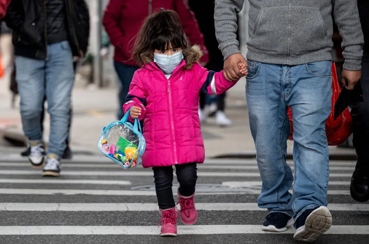 A girl, wearing a mask, walks down a street in the Corona neighborhood of Queens in New York City on April 14, 2020. (Johannes Eisele/AFP via Getty Images)