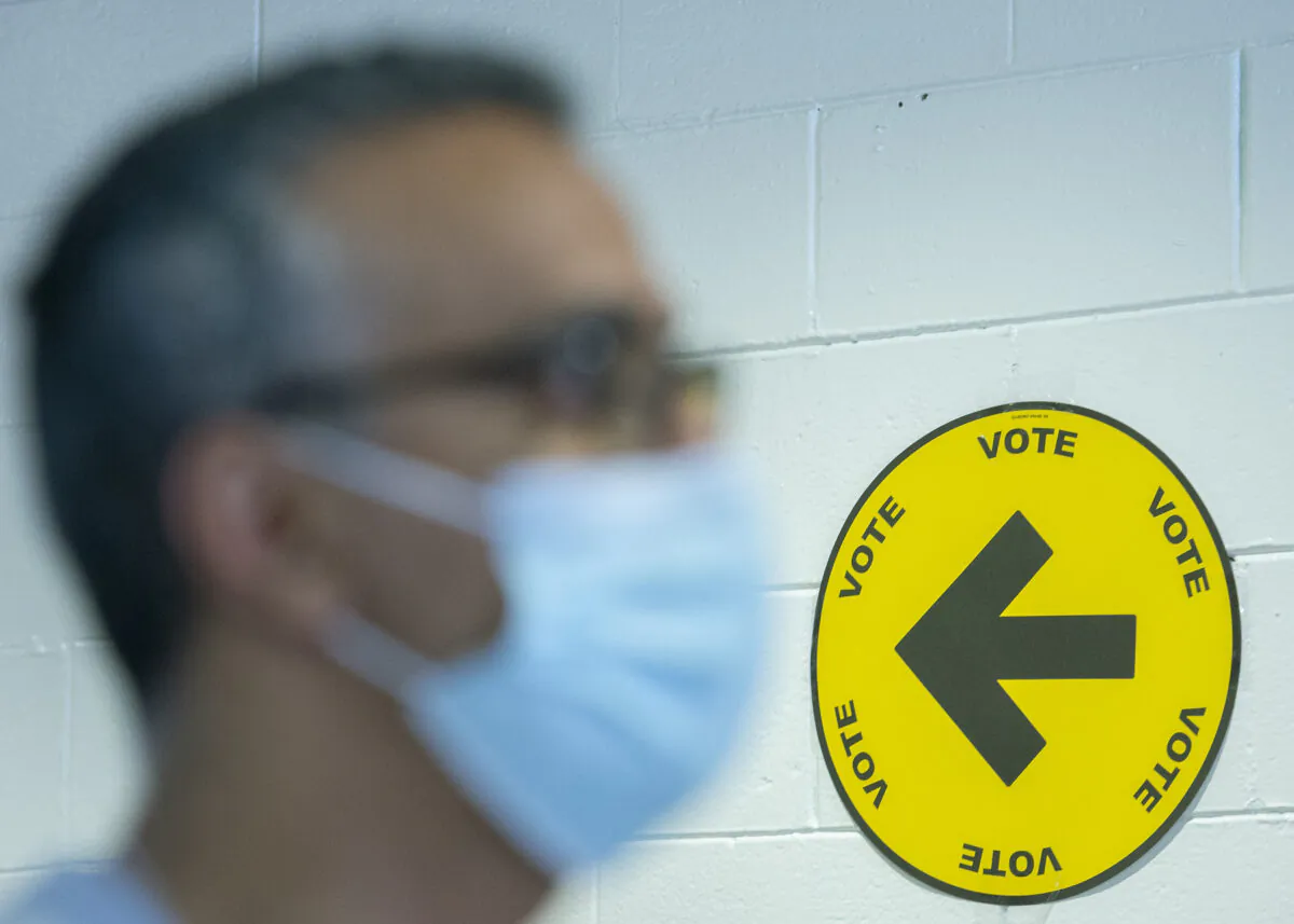 An elections Canada employee wears a face mask at a polling station on federal election day in Montreal, on Sept. 20, 2021. (The Canadian Press/Graham Hughes)