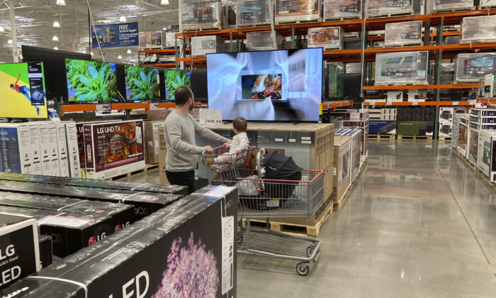 A shopper pushes a child in a cart while browsing big-screen televisions on display in the electronics section of a Costco warehouse in Lone Tree, Colo., on March 29, 2022. (David Zalubowski/AP Photo)