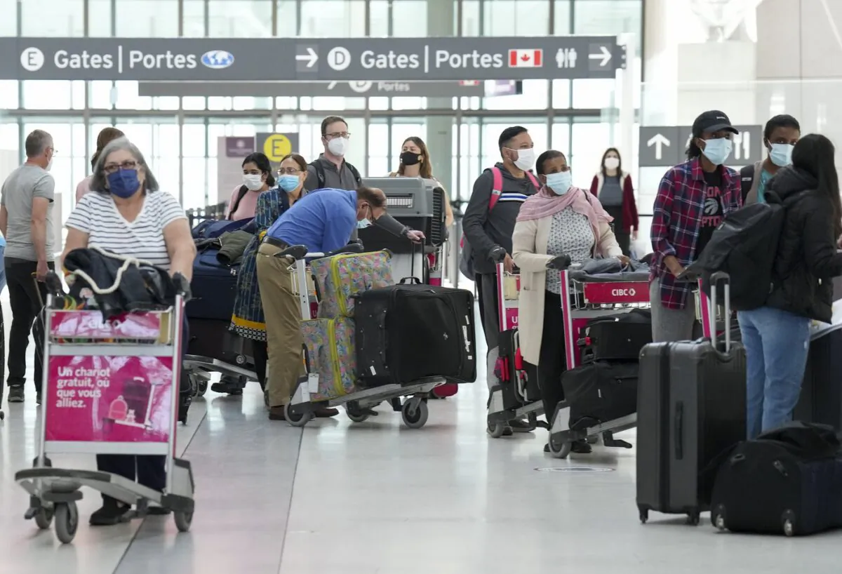 People wait in line to check in at Pearson International Airport in Toronto on May 12, 2022. (The Canadian Press/Nathan Denette)