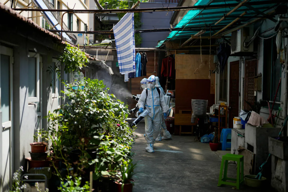 Workers in protective suits disinfect a closed residential area during a lockdown in Shanghai, on May 18, 2022. (Aly Song/Reuters)
