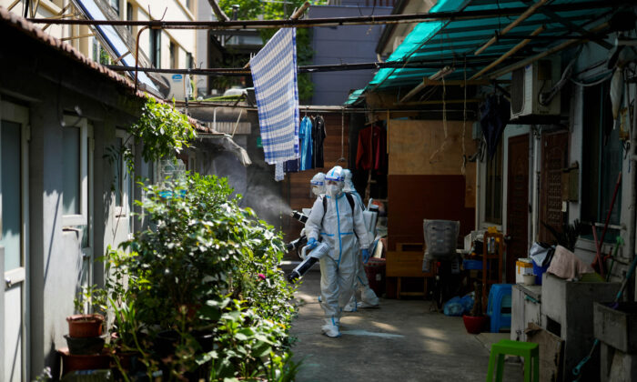 Workers in protective suits disinfect a closed residential area during a lockdown in Shanghai, on May 18, 2022. (Aly Song/Reuters)