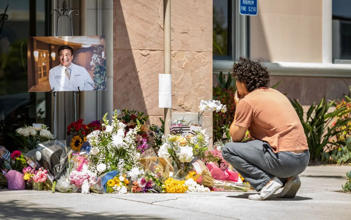 A young mourner at a memorial site for shooting victim Dr. John Cheng, whose photo sits on display at the entrance of South Bay Medical Group in Aliso Viejo, Calif. on May 17, 2022. (John Fredricks/The Epoch Times)