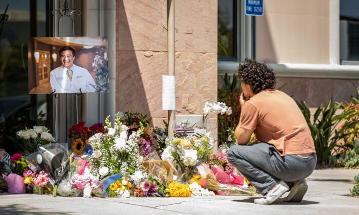 A young mourner at a memorial site for shooting victim Dr. John Cheng, whose photo sits on display at the entrance of South Bay Medical Group in Aliso Viejo, Calif. on May 17, 2022. (John Fredricks/The Epoch Times)
