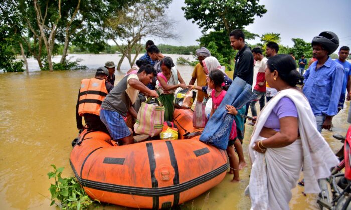People disembark a boat after they were evacuated from a flooded village in Nagaon district, in the northeastern state of Assam, India, on May 18, 2022. (Anuwar Hazarika/Reuters)