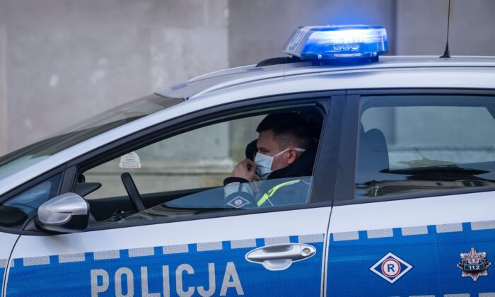 A police officer wearing a face mask patrols in his car during a protest by a few dozens of entrepreneurs in the center of Warsaw on March 31, 2020. (Wojtek Radawanski/AFP via Getty Images)