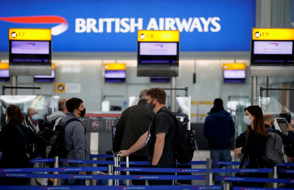Passengers stand in a queue to the British Airways check-in desks in the departures area of Terminal 5 at Heathrow Airport in London, on May 17, 2021. (John Sibley/Reuters)
