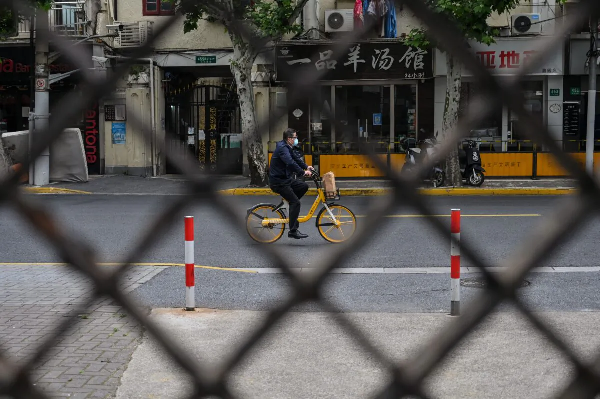 A man rides a bicycle on a street seen through a fence of a compound in lockdown during a COVID-19 lockdown in the Jing'an district in Shanghai on May 19, 2022. (Hector Retamal/AFP via Getty Images)