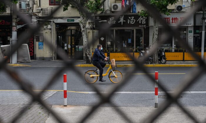 A man rides a bicycle on a street seen through a fence of a compound in lockdown during a COVID-19 lockdown in the Jing'an district in Shanghai on May 19, 2022. (Hector Retamal/AFP via Getty Images)