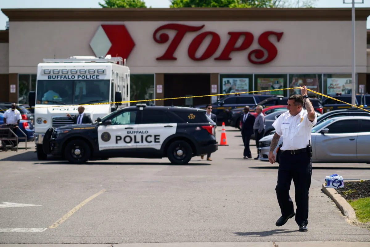 A police officer lifts the tape cordoning off the scene of a shooting at a supermarket, in Buffalo, N.Y., on May 15, 2022. (AP Photo/Matt Rourke)