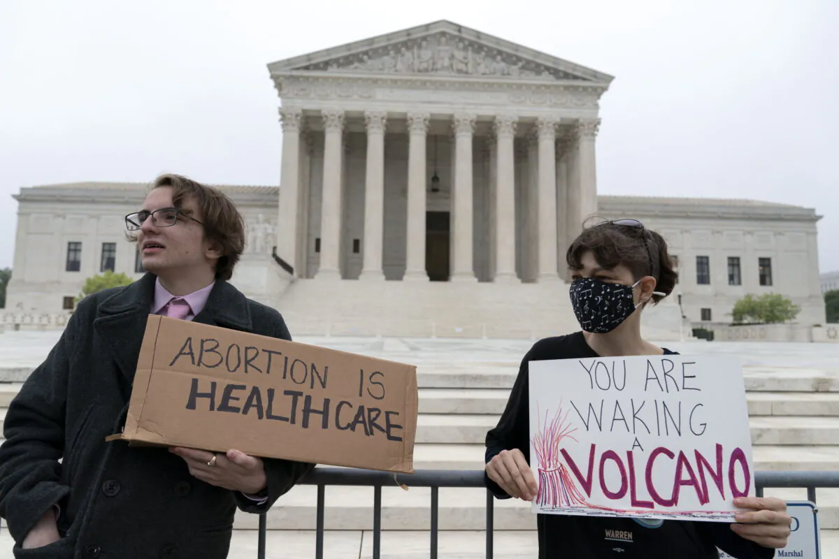 Demonstrators Jonah Smith from California, left, and Robin G. from the D.C. area, stand outside the U.S. Supreme Court on May 3, 2022. (AP Photo/Jose Luis Magana)