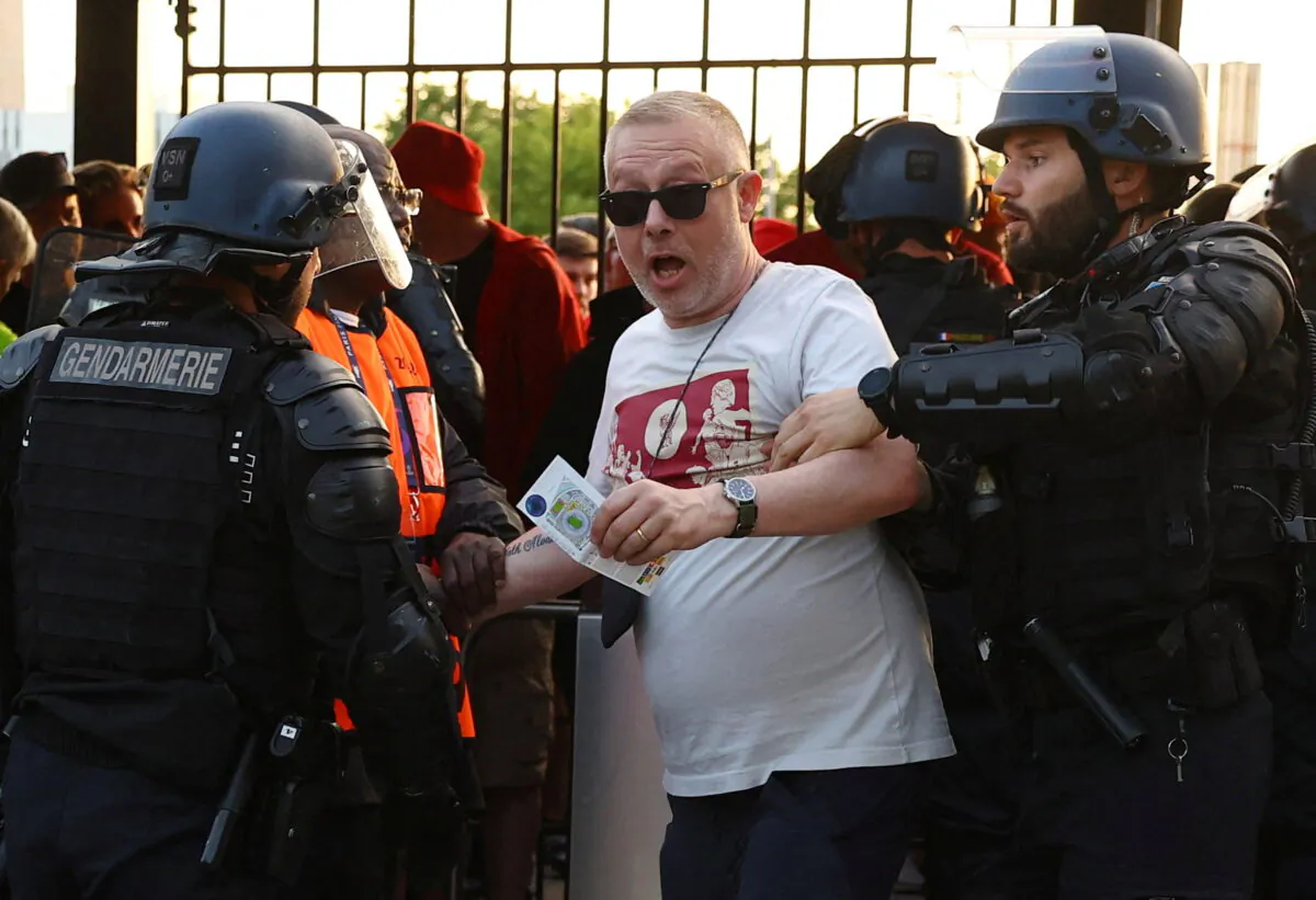 A fan is held by a police officer and a steward inside the stadium by the turnstiles as the Champions League final match between Liverpool and Real Madrid is delayed at Stade de France in Saint-Denis near Paris, France, on  May 28, 2022. (Kai Pfaffenbach/Reuters)