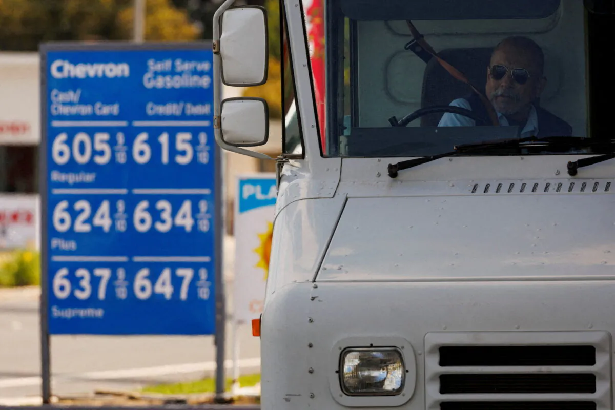 A U.S. postal worker puts his seatbelt on after filing up his vehicle at a gas station in Garden Grove, Calif., on March 29, 2022. (Mike Blake/Reuters)