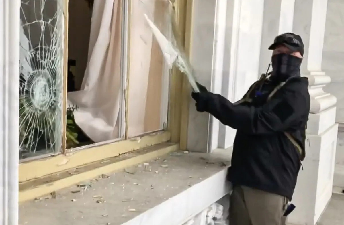 A suspicious actor vandalized a Capitol window on Jan. 6, 2021. He has not been placed on the FBI wanted list nor has he been arrested or charged. (Bobby Powell/Screenshot via The Epoch Times)