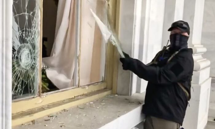 A suspicious actor vandalized a Capitol window on Jan. 6, 2021, and encouraged others to open it up further. He was captured on video but has not been placed on the FBI wanted list. (Bobby Powell/Screenshot by The Epoch Times)