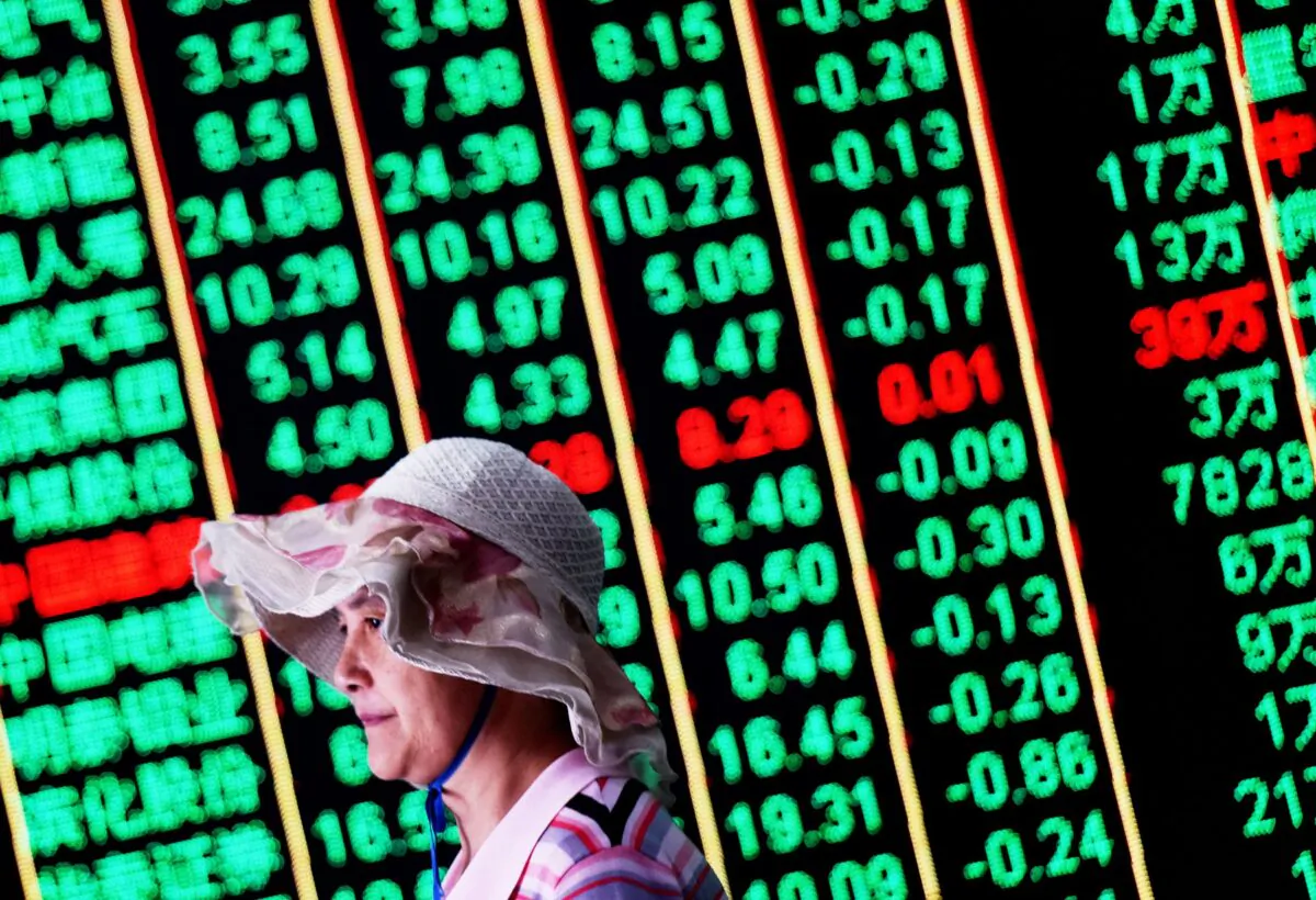 A woman walks past a board showing China’s stock market movement. (AFP via Getty Images)