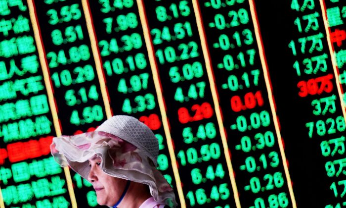 A woman walks past a board showing China’s stock market movement. (AFP via Getty Images)