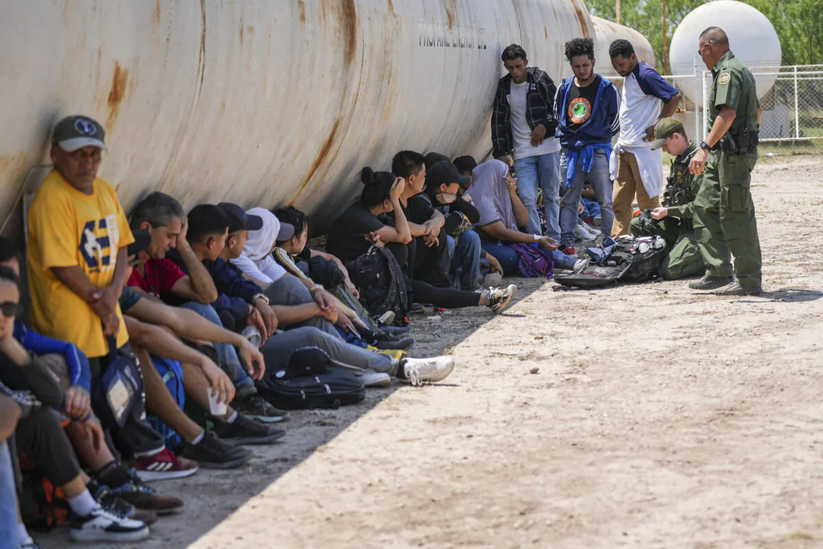 Border Patrol agents administer medical assistance to a woman while apprehending a large group of illegal immigrants near Eagle Pass, Texas, on May 20, 2022. (Charlotte Cuthbertson/The Epoch Times)