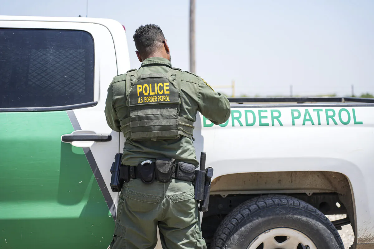 A Border Patrol agent fills out paperwork while detaining a large group of illegal immigrants near Eagle Pass, Texas, on May 20, 2022. (Charlotte Cuthbertson/The Epoch Times)