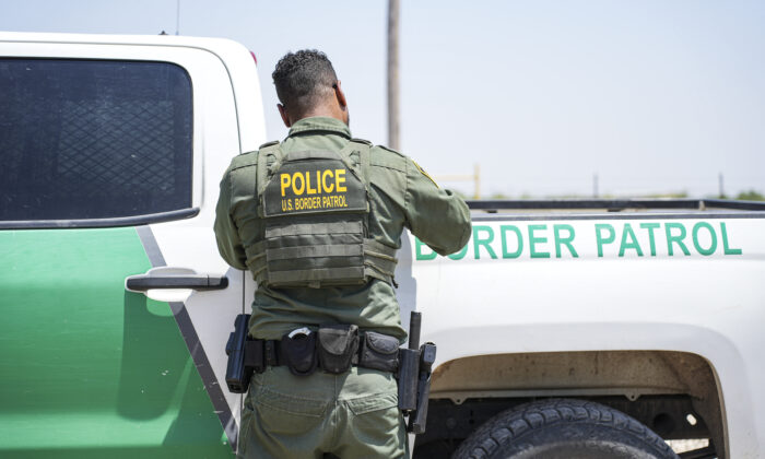 A Border Patrol agent fills out paperwork while detaining a large group of illegal immigrants near Eagle Pass, Texas, on May 20, 2022. (Charlotte Cuthbertson/The Epoch Times)