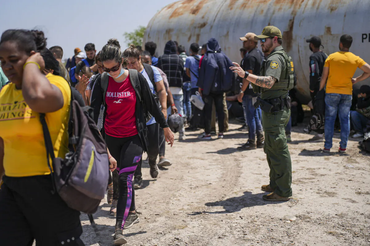 A Border Patrol agent organizes a large group of illegal immigrants near Eagle Pass, Texas, on May 20, 2022. (Charlotte Cuthbertson/The Epoch Times)