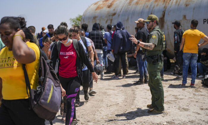 A Border Patrol agent organizes a large group of illegal immigrants near Eagle Pass, Texas, on May 20, 2022. (Charlotte Cuthbertson/The Epoch Times)