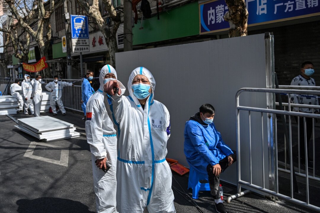 A policeman wearing protective clothing reacts in an area where barriers are being placed to close off streets around a locked down neighborhood in Shanghai on March 15, 2022. (Hector Retamal/AFP via Getty Images)