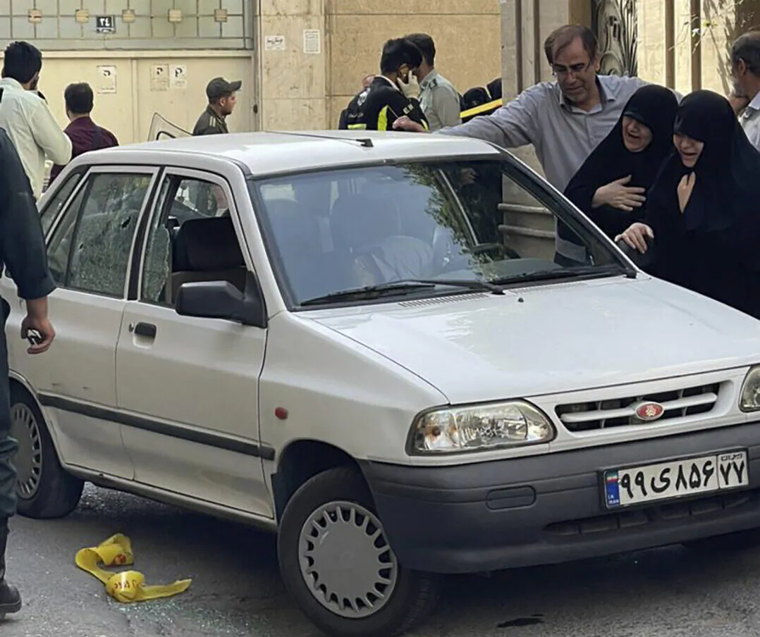 Family members of Col. Hassan Sayyad Khodaei weep over his body at his car after being shot by two assailants in Tehran, Iran, on May 22, 2022. (IRNA via AP)