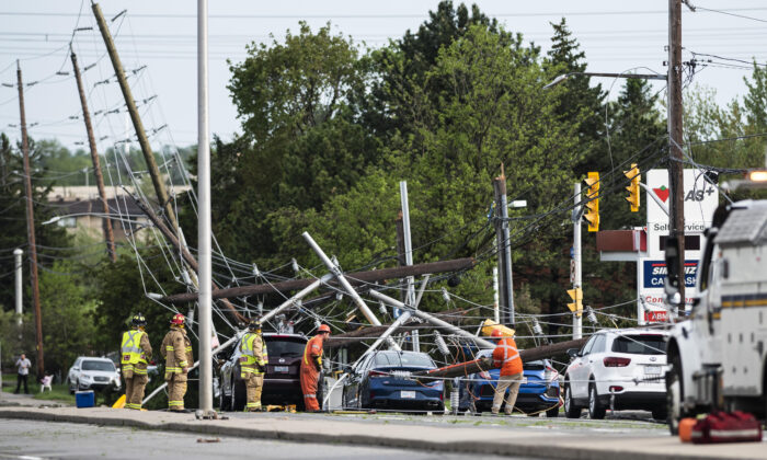 Firefighters and utility workers work among downed power lines, poles, and traffic lights that came down onto the roadway and onto motorists during a major storm, on Merivale Road in Ottawa, on May 21, 2022. (Justin Tang/The Canadian Press)