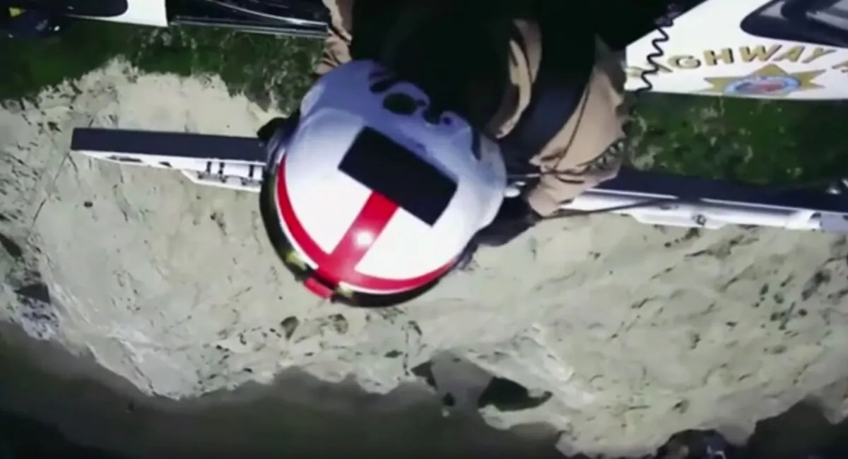 An officer being lowered from a helicopter to rescue the man that was balanced on a ledge in Daly City, Calif., on May 19, 2022. (California Highway Patrol via AP/Screenshot via The Epoch Times)