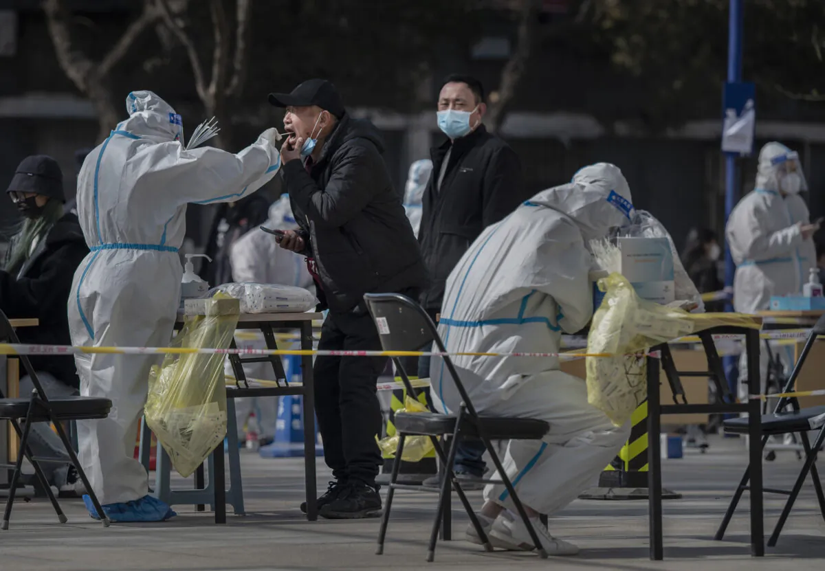 Health care workers in protective clothing conduct large-scale sampling of local residents for nucleic acid testing after a new Omicron surge in Beijing in April 2022. The CCP's COVID lockdowns and the Russia-Ukraine war have dragged down global economic growth and pushed inflation to new highs. (Kevin Frayer/Getty Images)
