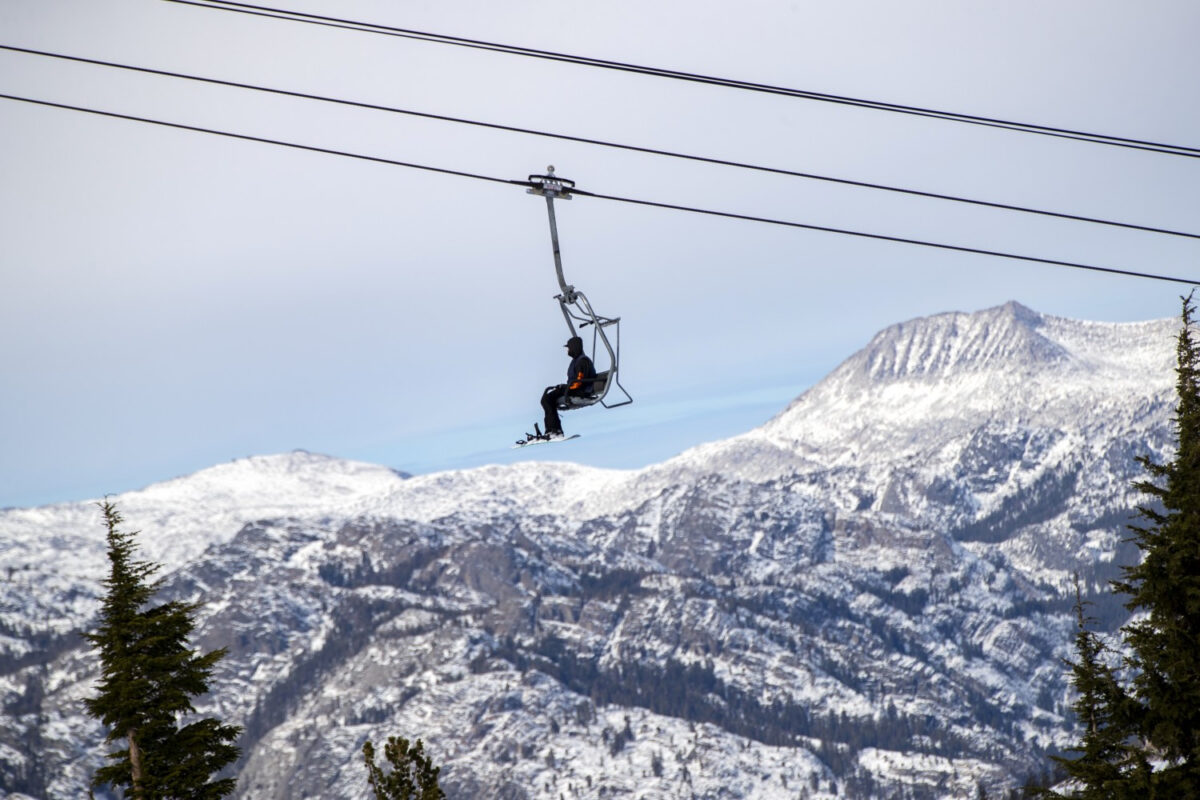A solo snowboarder rides a chair lift wearing his face coverings over the winter scenery at Mammoth Mountain on Nov. 20, 2020, in Mammoth Lakes, California. The resort's season has been extended due to a recent hearty snowfall. (Gina Ferazzi/Los Angeles Times/TNS)