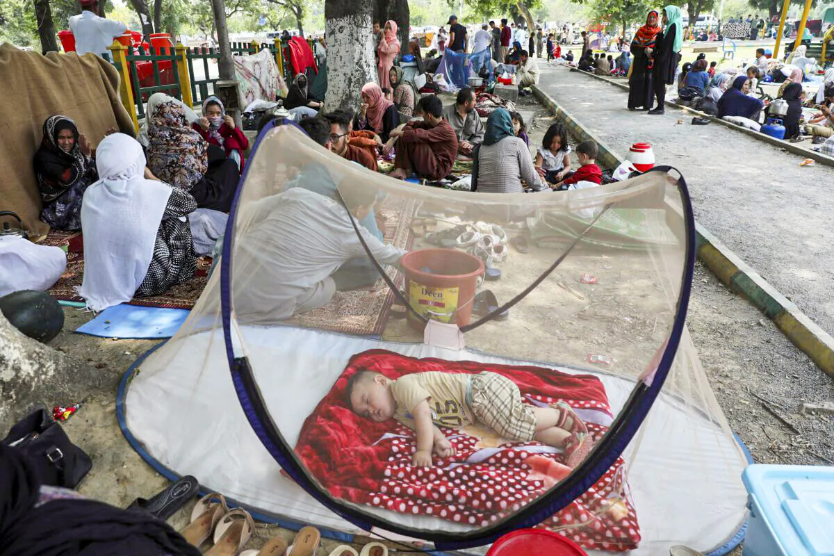 An Afghan boy sleeps beneath a mosquito net as those displaced people have put up makeshift tents on the ground seeking to receive asylum from the United Nations High Commissioner for Refugees (UNHCR) outside the Islamabad Press Club in Islamabad, on May 9, 2022. (Rahmat Gul/AP Photo)