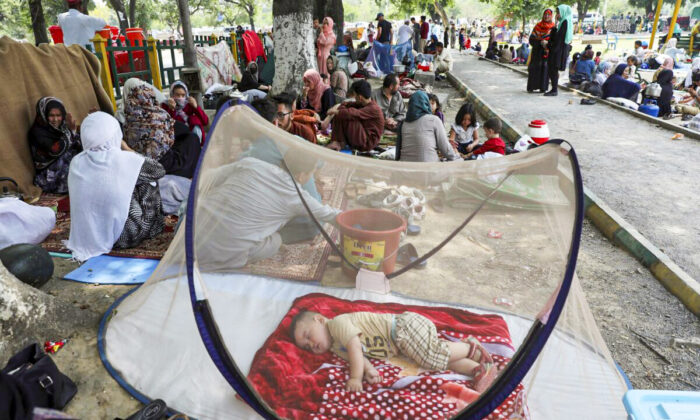 An Afghan boy sleeps beneath a mosquito net as those displaced people have put up makeshift tents on the ground seeking to receive asylum from the United Nations High Commissioner for Refugees (UNHCR) outside the Islamabad Press Club in Islamabad, on May 9, 2022. (Rahmat Gul/AP Photo)