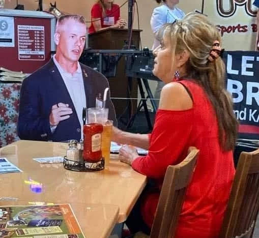 Cathi Chamberlain takes a break to "strategize" about the campaign with her companion cardboard cutout of January 6 prisoner and candidate for Florida State House of Representatives at at local Florida restaurant.