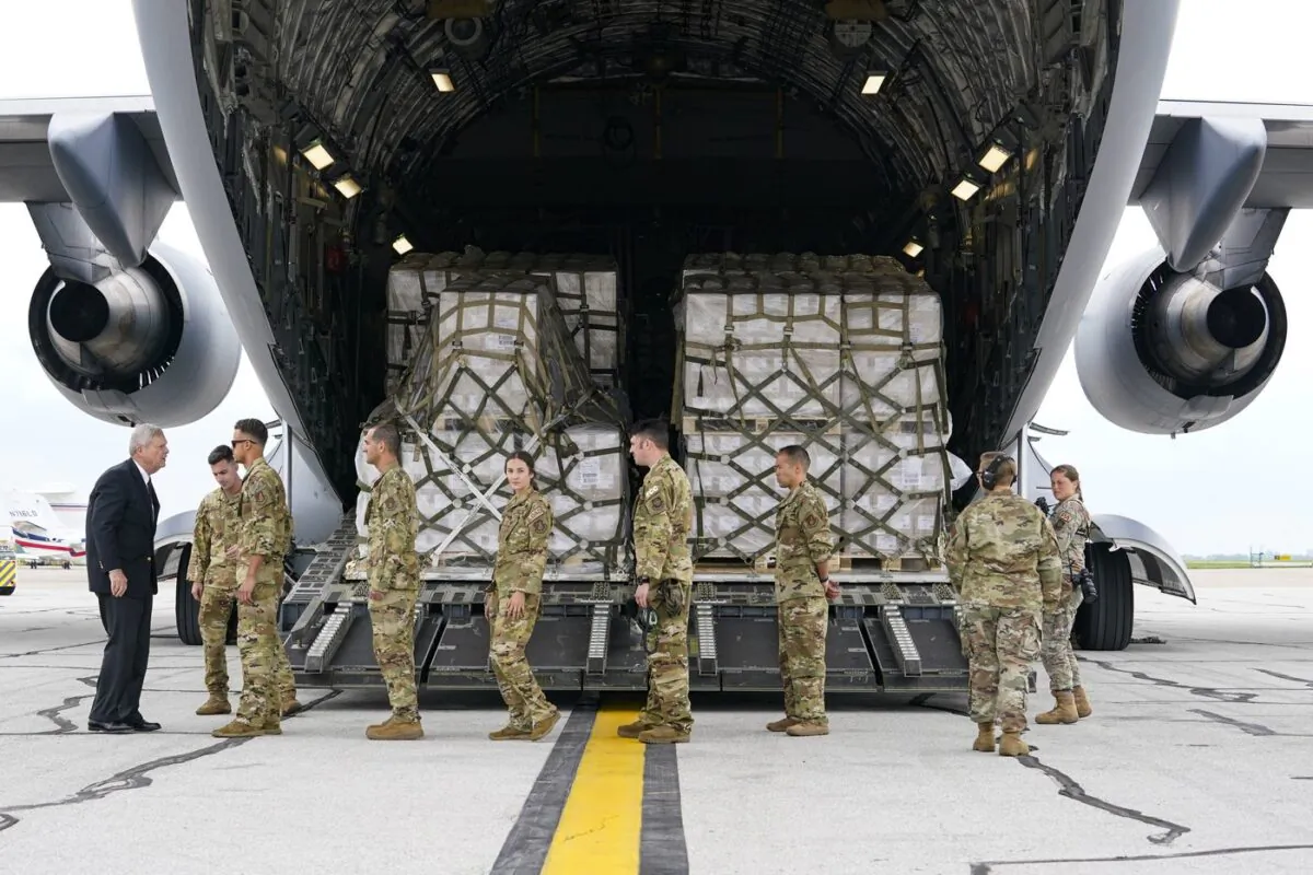 Agriculture Secretary Tom Vilsack, (L), greets crew members of a C-17 that delivered a plane load of baby formula at the Indianapolis International Airport in Indianapolis, on May 22, 2022. (AP/Michael Conroy)