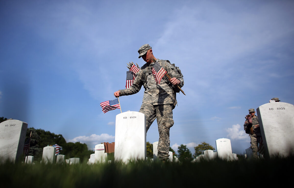A member of the 3rd U.S. Infantry Regiment places American flags at the graves of U.S. soldiers buried in Section 60 at Arlington National Cemetery in preparation for Memorial Day in Arlington, Va., on May 24, 2012.  (Win McNamee/Getty Images)