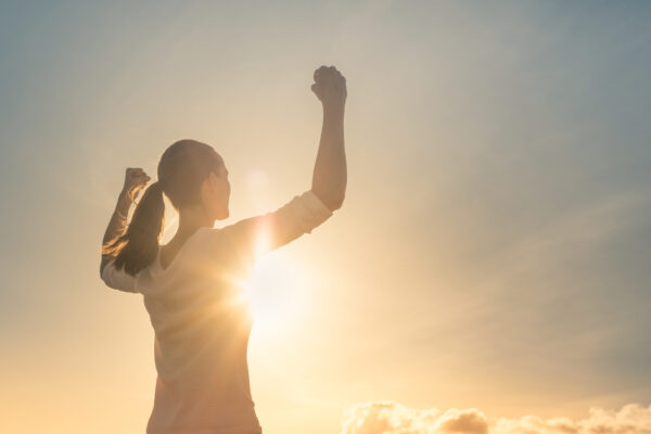Strong woman, Winning, success , and life goals concept. Young woman with arms flexed facing the sunset.