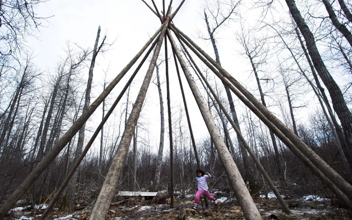 An indigenous girl plays inside a teepee at a young bush camp in the northern Ontario First Nations reserve in Attawapiskat, Ont., on April 20, 2016. (The Canadian Press/Nathan Denette)
