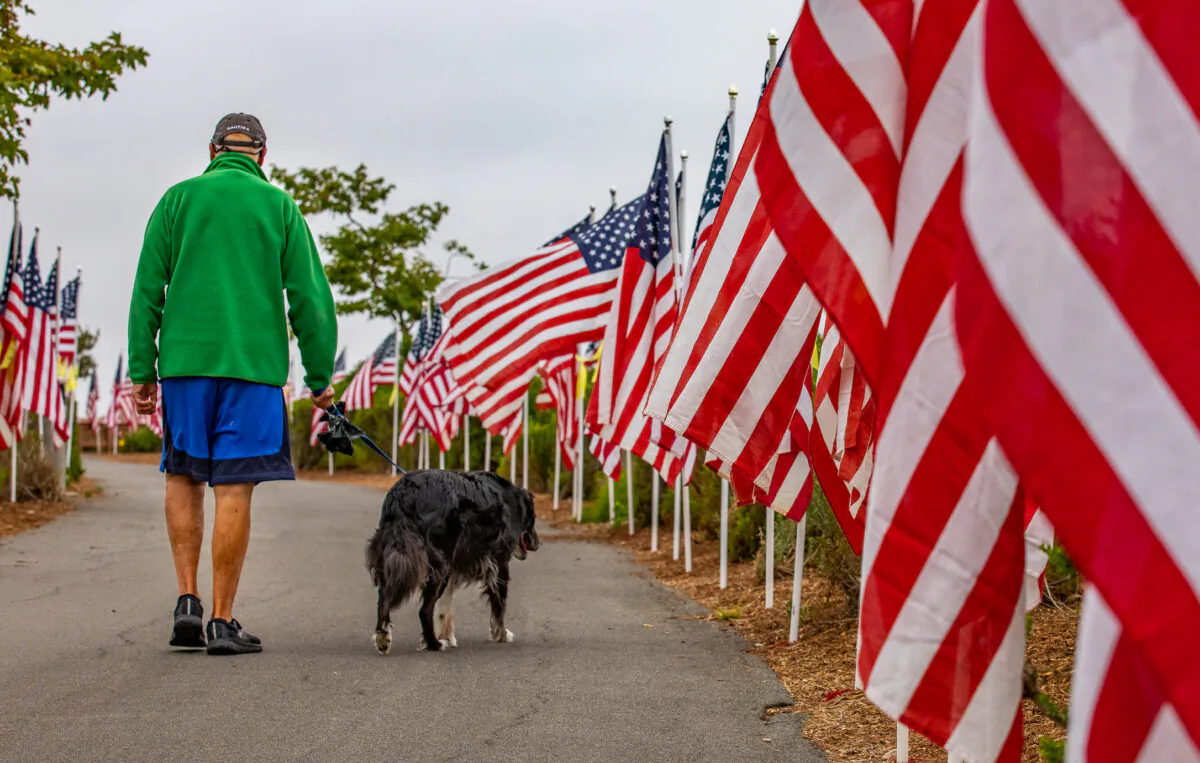 People walk through a display of 1776 American flags in Castaways Park in Newport Beach, Calif., on May 23, 2022. (John Fredricks/The Epoch Times)