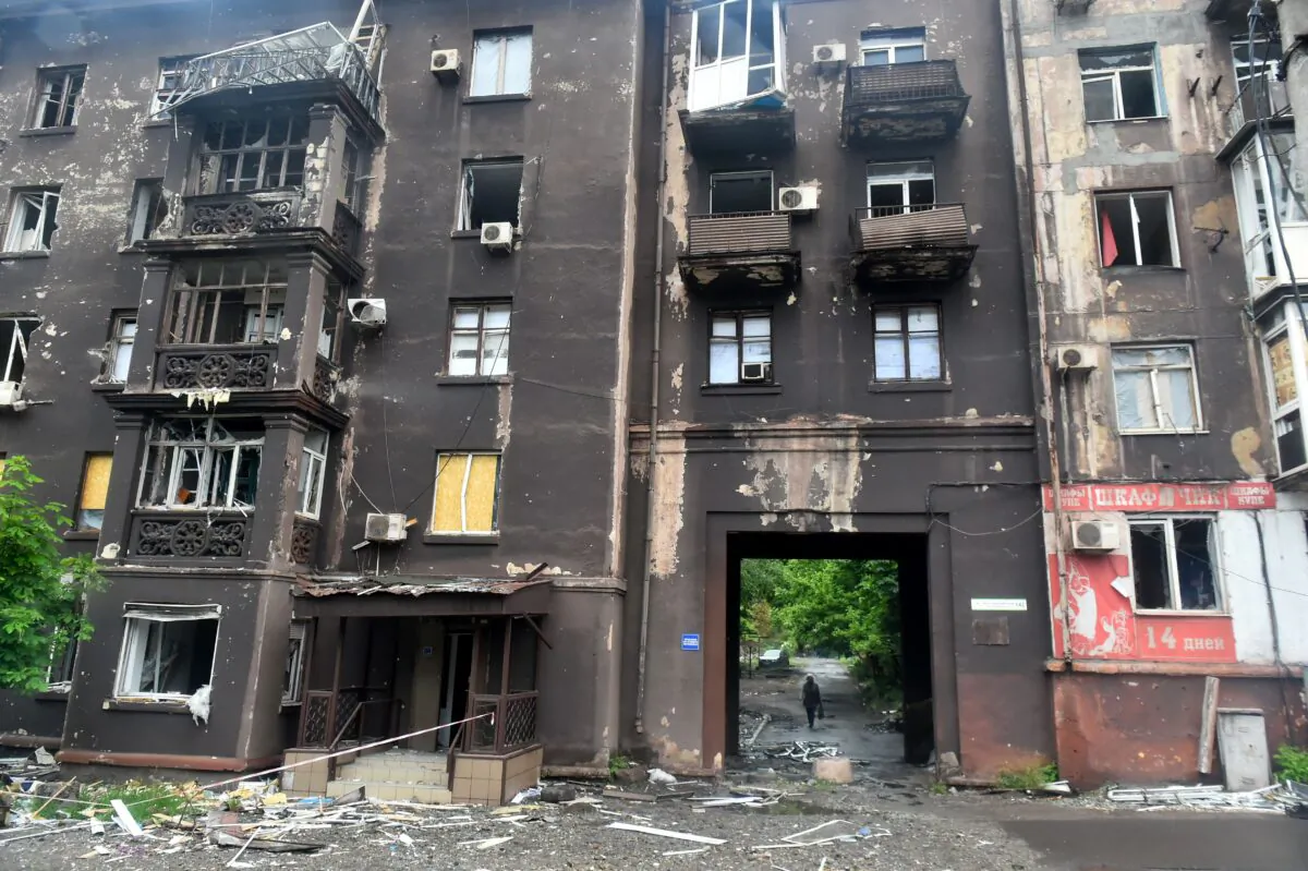 A woman walks behind a burnt residential building in Ukraine's port city of Mariupol on May 18, 2022. (Olga Maltseva/AFP via Getty Images)