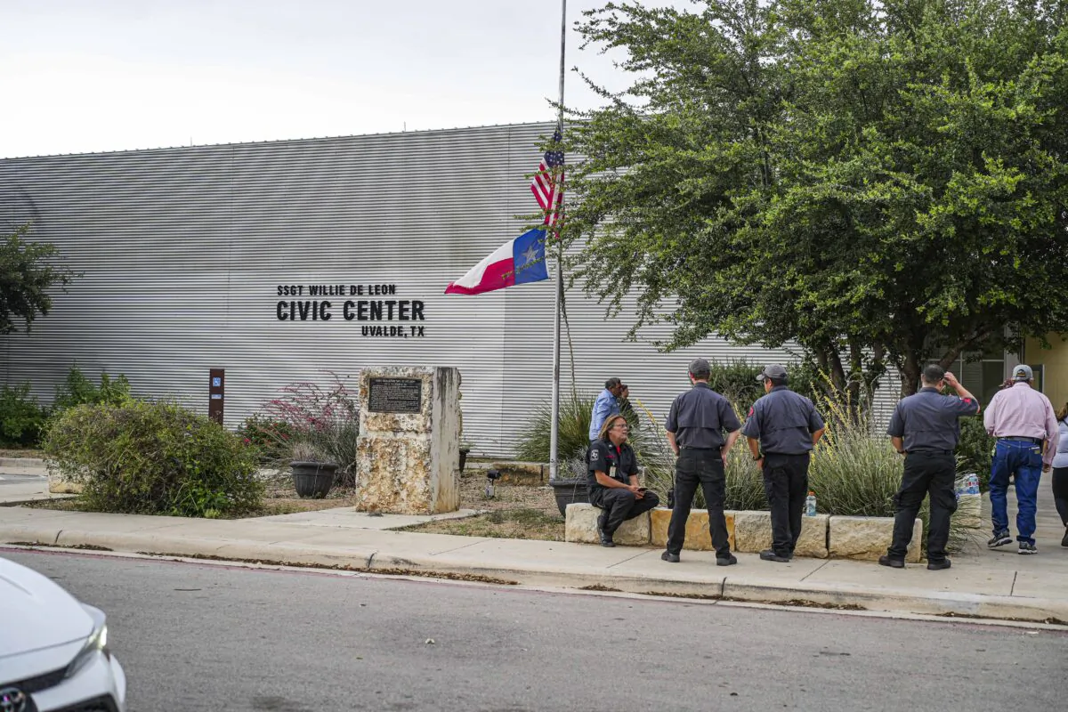 A man lowers the U.S. and Texas flags to half-staff outside the Uvalde Civic Center following a mass shooting at an elementary school, in Uvalde, Texas, on May 24, 2022. (Charlotte Cuthbertson/The Epoch Times)