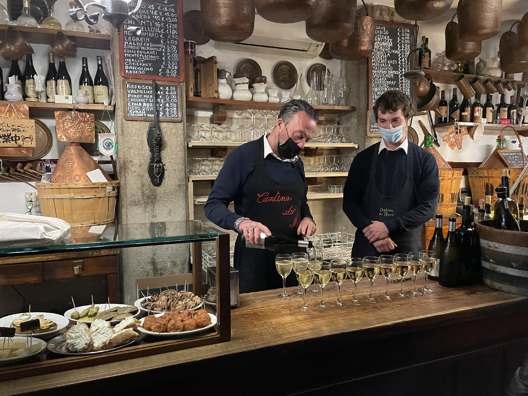 Local Prosecco is poured at Cantina do Mori beneath metal pails that were once used to gather fresh water. 