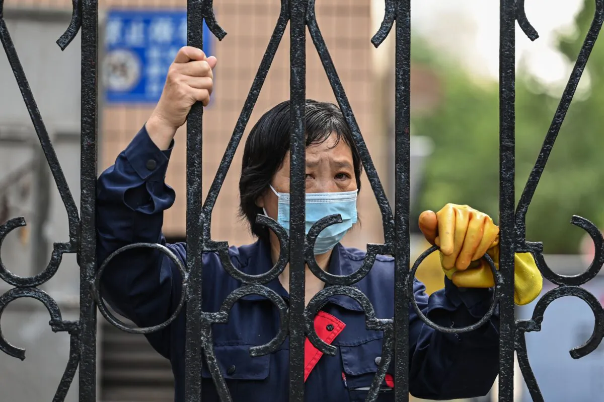 A worker looks past a fence in a compound during a COVID-19 lockdown in the Jing'an district of Shanghai on May 25, 2022. (Hector Retamal/AFP via Getty Images)