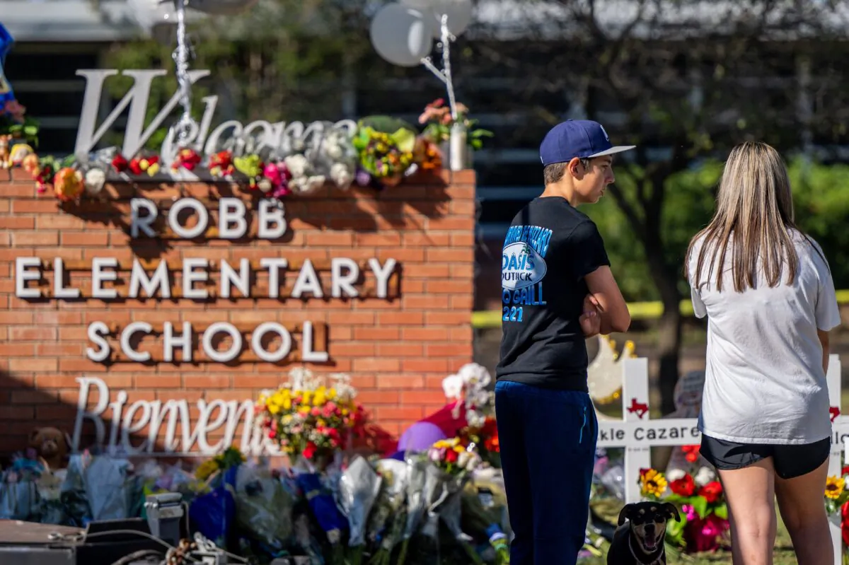 Young adults stand looking at a memorial at Robb Elementary School following a mass shooting in Uvalde, Texas, on May 26, 2022. (Brandon Bell/Getty Images)